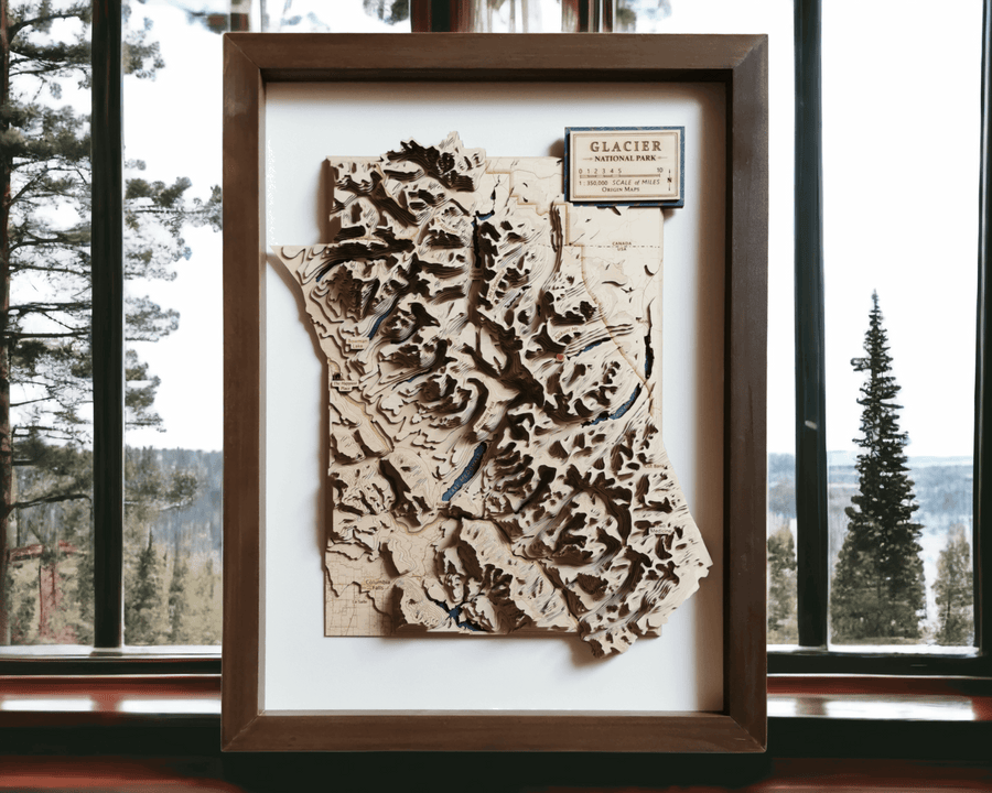 Wooden topographic contour map art of glacier national park in montana usa and canada. The map is framed and is resting on a shelf overlooking a picturesque forest