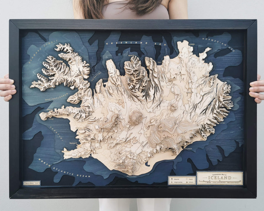 Wooden 3D topographic map art of Iceland in a wooden frame held by a girl