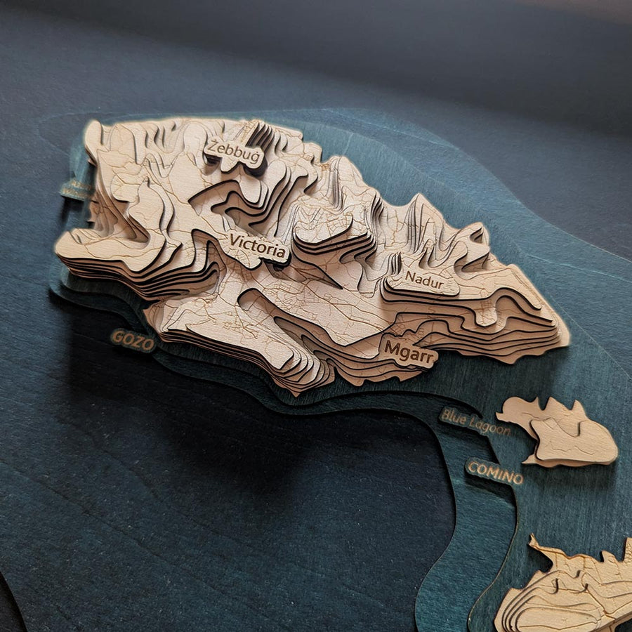 Wooden topographic map of the island of Gozo of Malta with labeled areas on a dark blue background