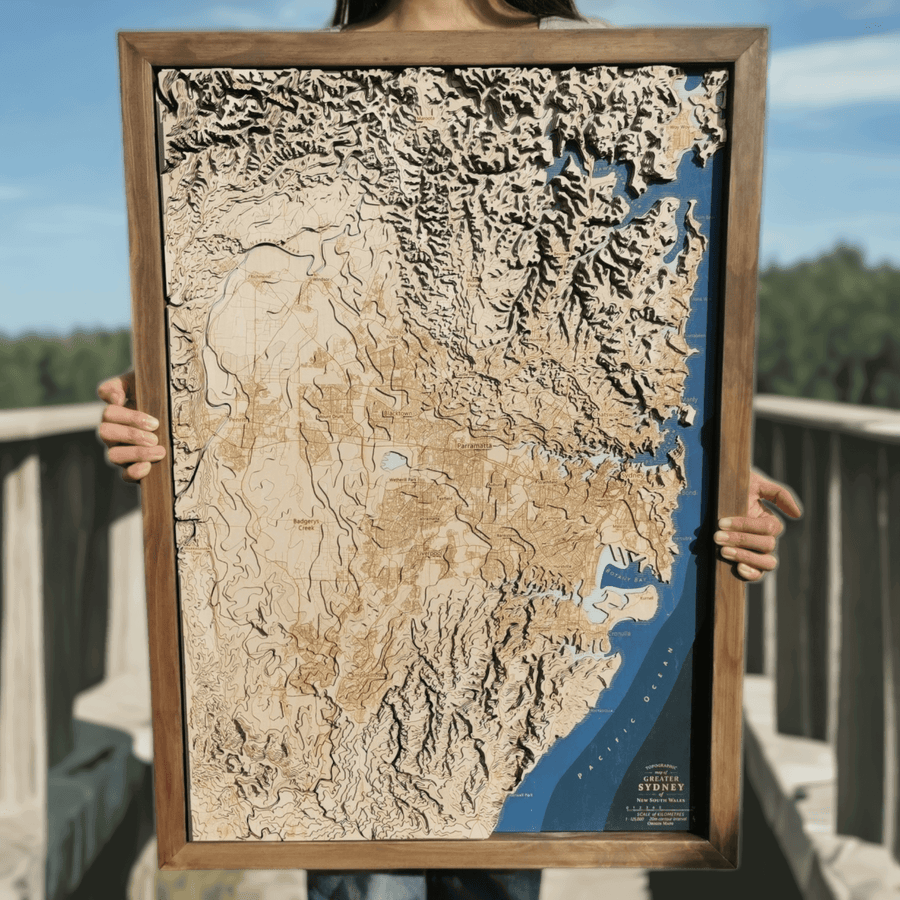 Sydney nsw australia wooden map art in a brown frame, held by a young pretty girl on a walkway