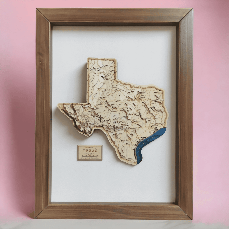 Wooden Handcrafted Topographic Map Art of Texas state of the usa. In a brown wooden frame with a pink backdrop