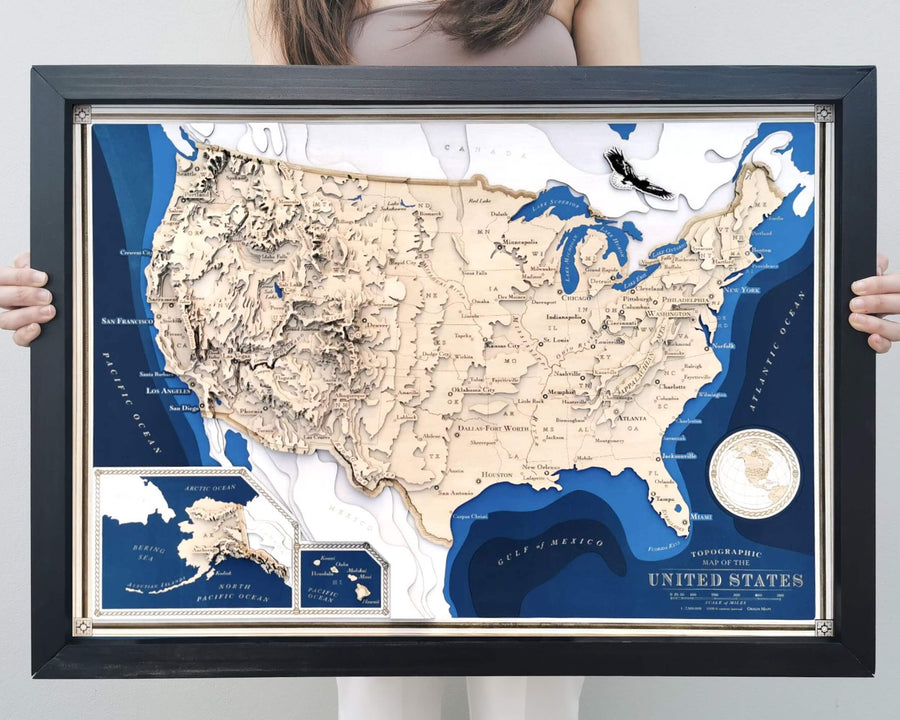 Wooden topographic contour map of the USA showing all 50 states. The map is framed and held by a young beautiful girl