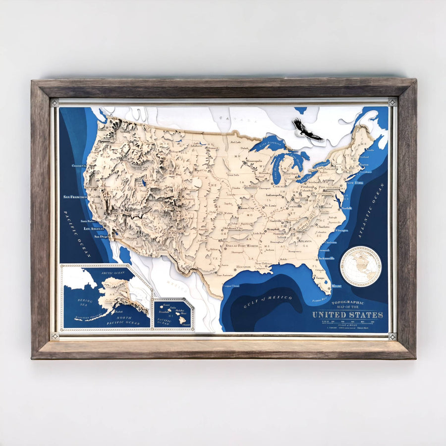 A wooden topographic map of the entire United States featuring the lower 48, Alaska and Hawaii. It is in an elegant brown hardwood frame