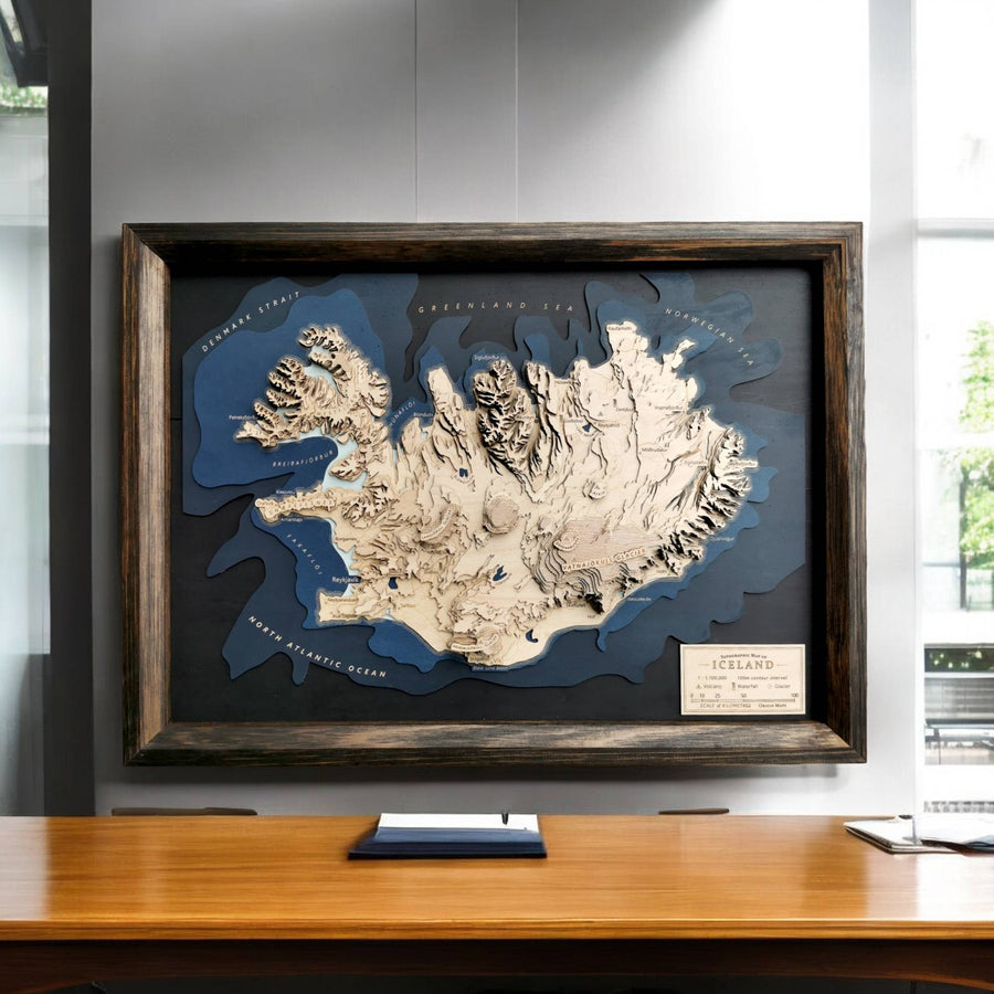 Wooden topographic map of Iceland in a black wooden frame over a office desk as a piece of art